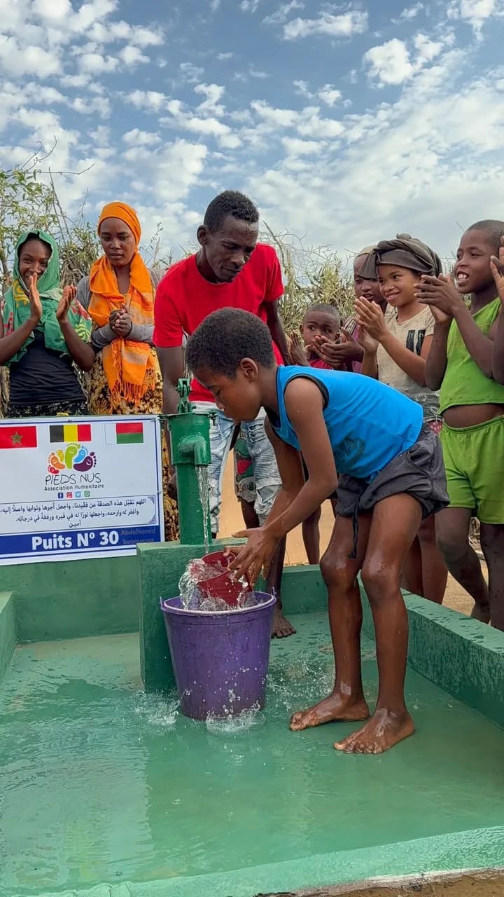 Une fille puise l'eau au puits n° 30 sous les applaudissements des habitants