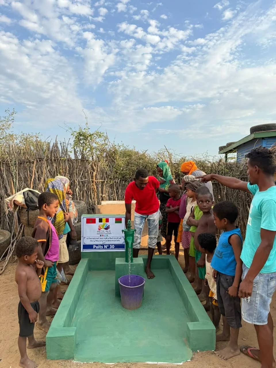 Habitants d'un village malgache rassemblés autour du puits n° 30 et de son bassin vert