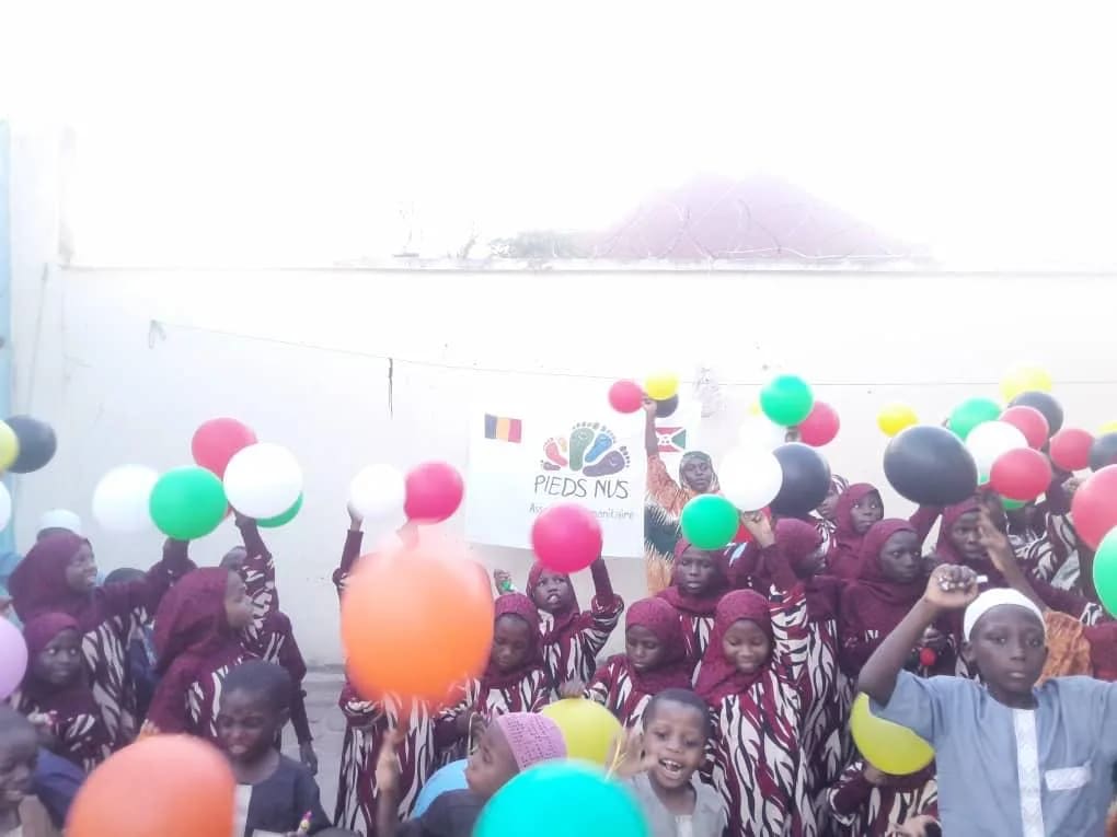 Enfants et ballons colorés devant la bannière Pieds Nus à Bujumbura