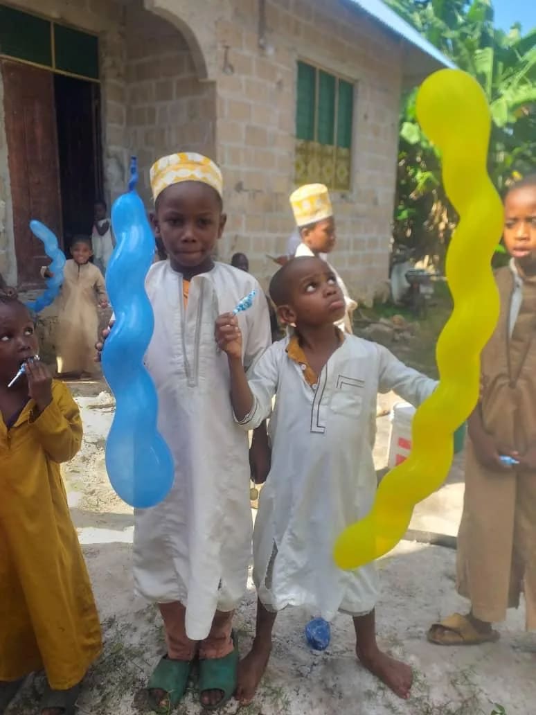 Garçons en tenue traditionnelle blanche, ballons à la main, devant une maison de Zanzibar