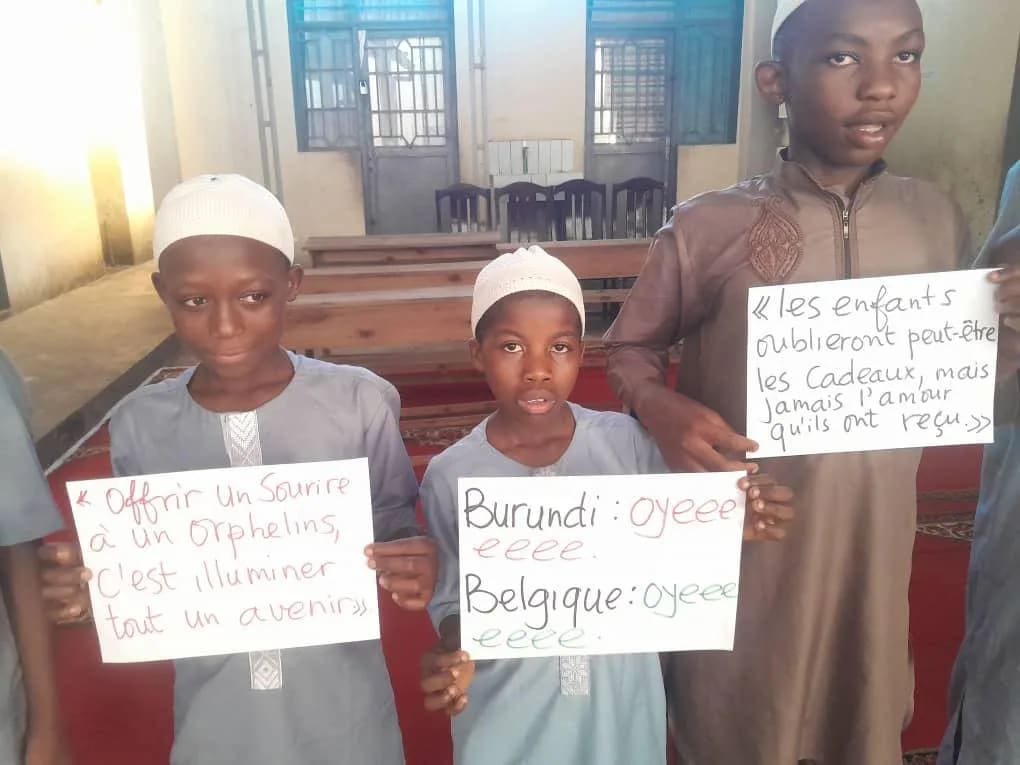 Drie jongens houden handgeschreven borden vast: "Burundi: hoera, België: hoera"