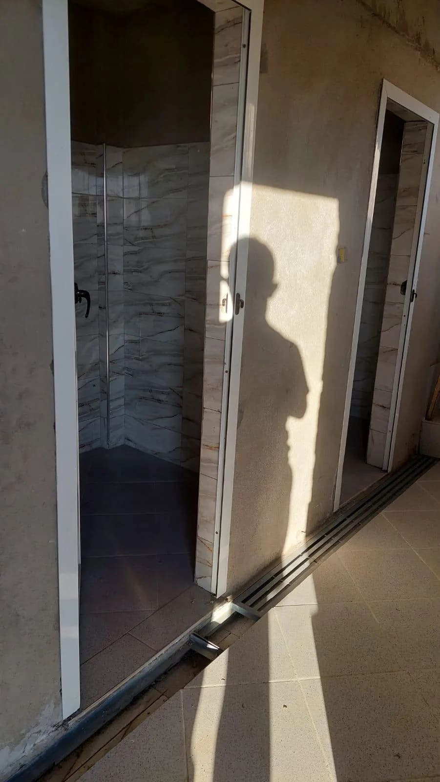 Intérieur d'un bloc sanitaire récemment aménagé : douche carrelée et portes neuves