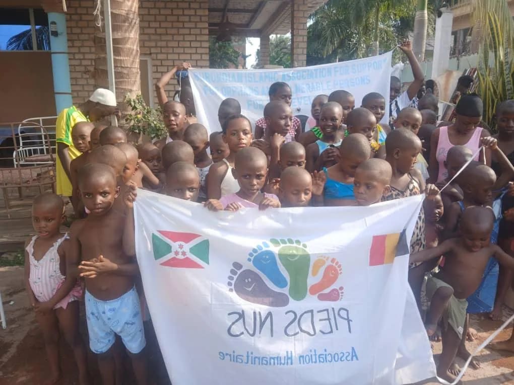 Enfants rassemblés autour d'une bannière Pieds Nus aux drapeaux du Burundi et de la Belgique