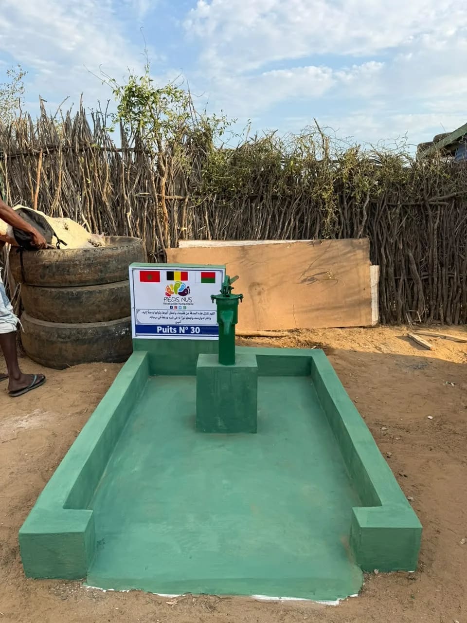 Le puits n° 30 terminé : bassin vert, pompe à main et plaque aux drapeaux du Maroc, de la Belgique et de Madagascar