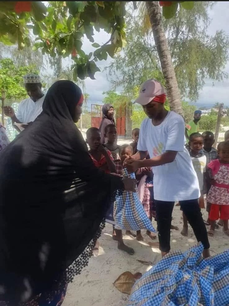 Des bénévoles remettent des vêtements à des enfants dans un village de Zanzibar, au bord de la plage